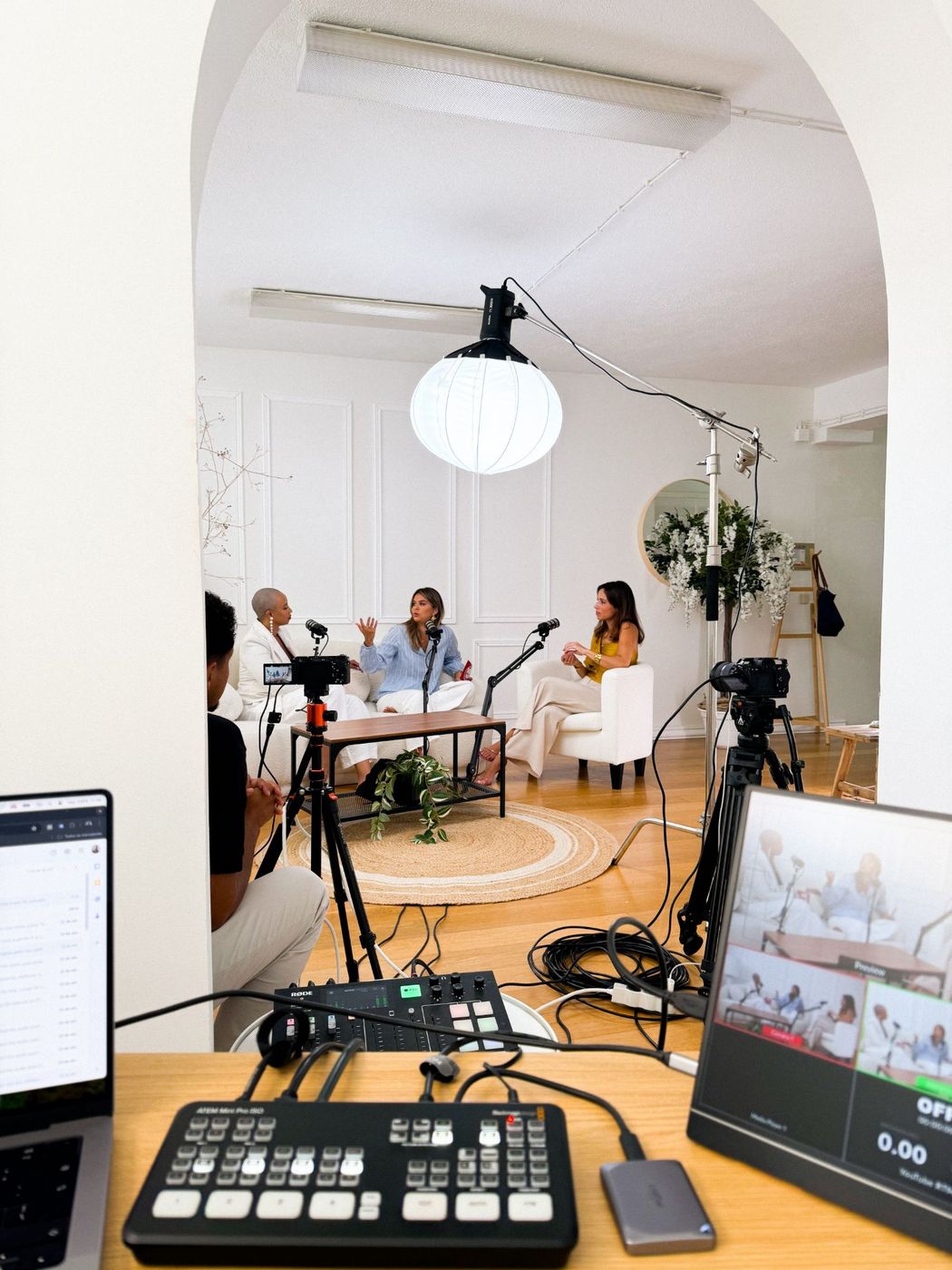 Podcast gravado numa sala branca com arcos e mesa redonda
