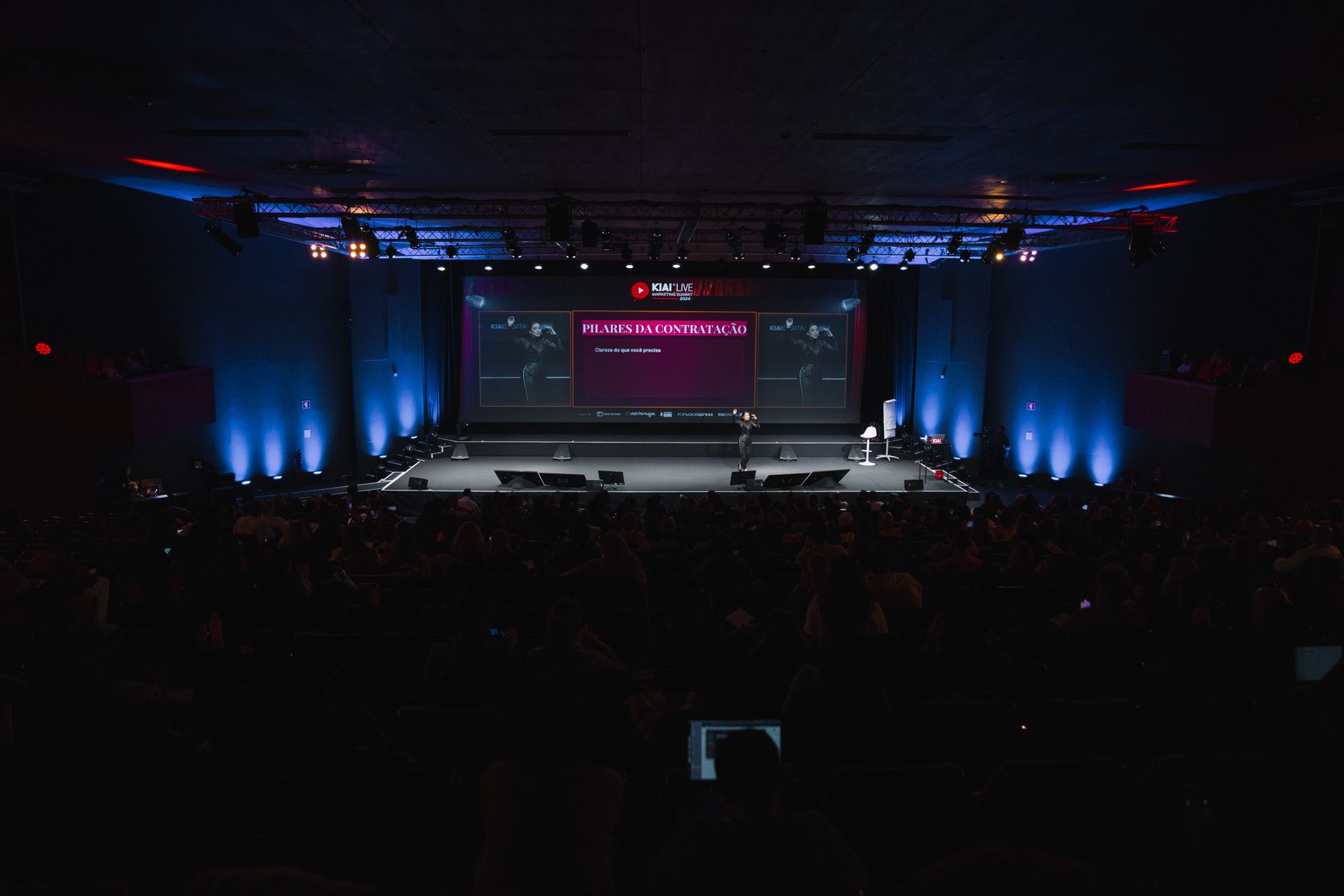 Palco de um evento corporativo com luz azul e plateia